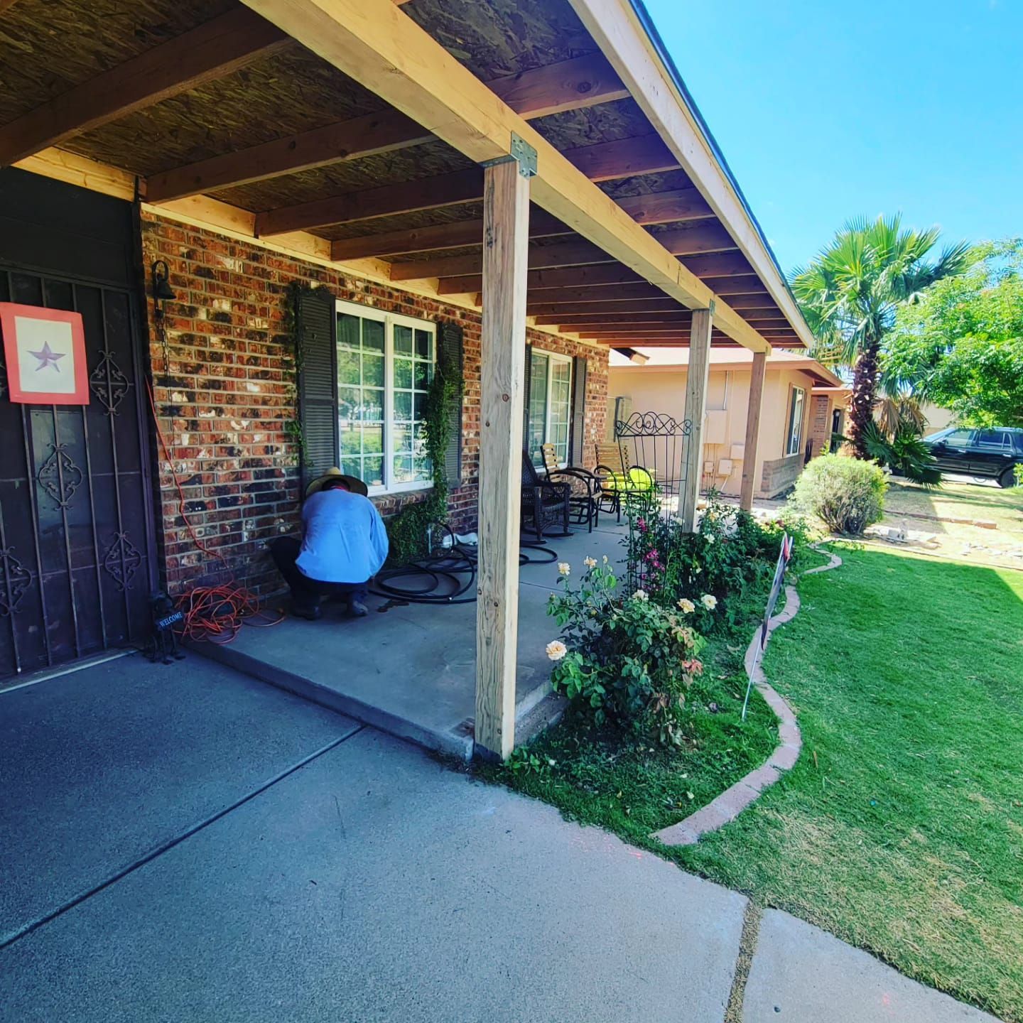 A man sits on the porch of a brick house