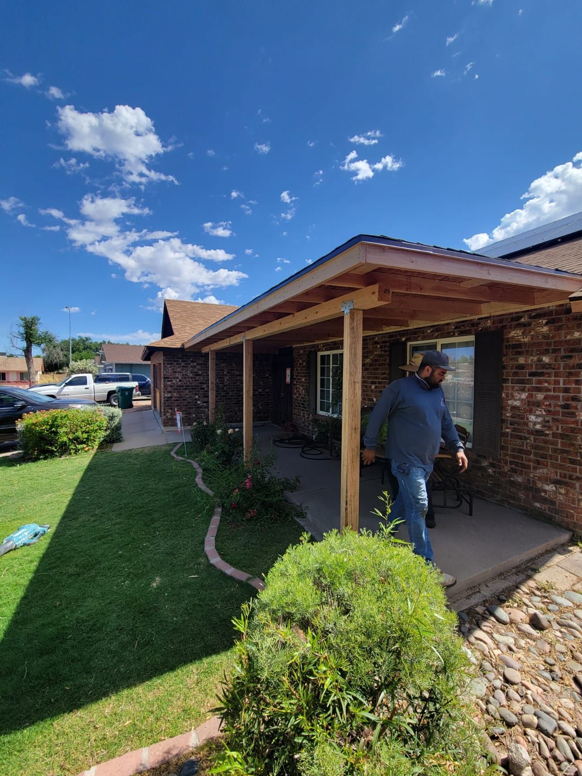A man is standing on a porch in front of a brick house.