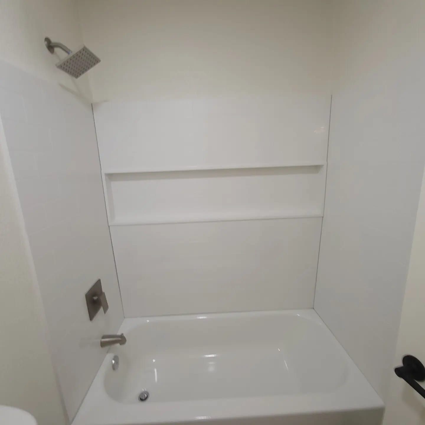 A white bathtub in a bathroom with a shower head