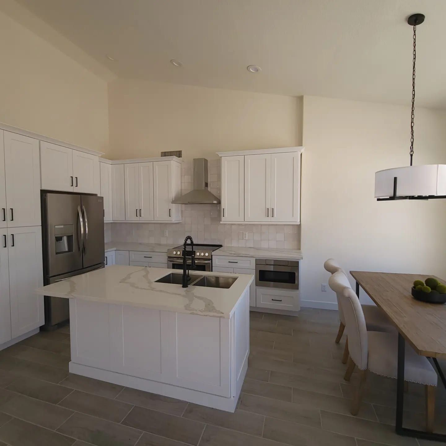 A kitchen with white cabinets and a large island in the middle