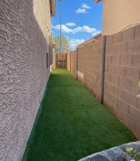 A narrow alleyway between two buildings with a brick wall and grass.