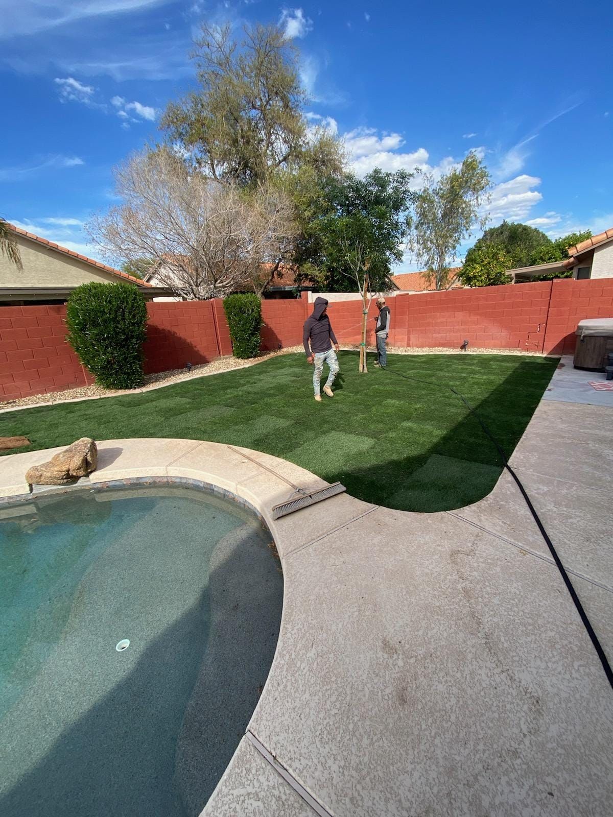 A man is standing in a backyard next to a pool.