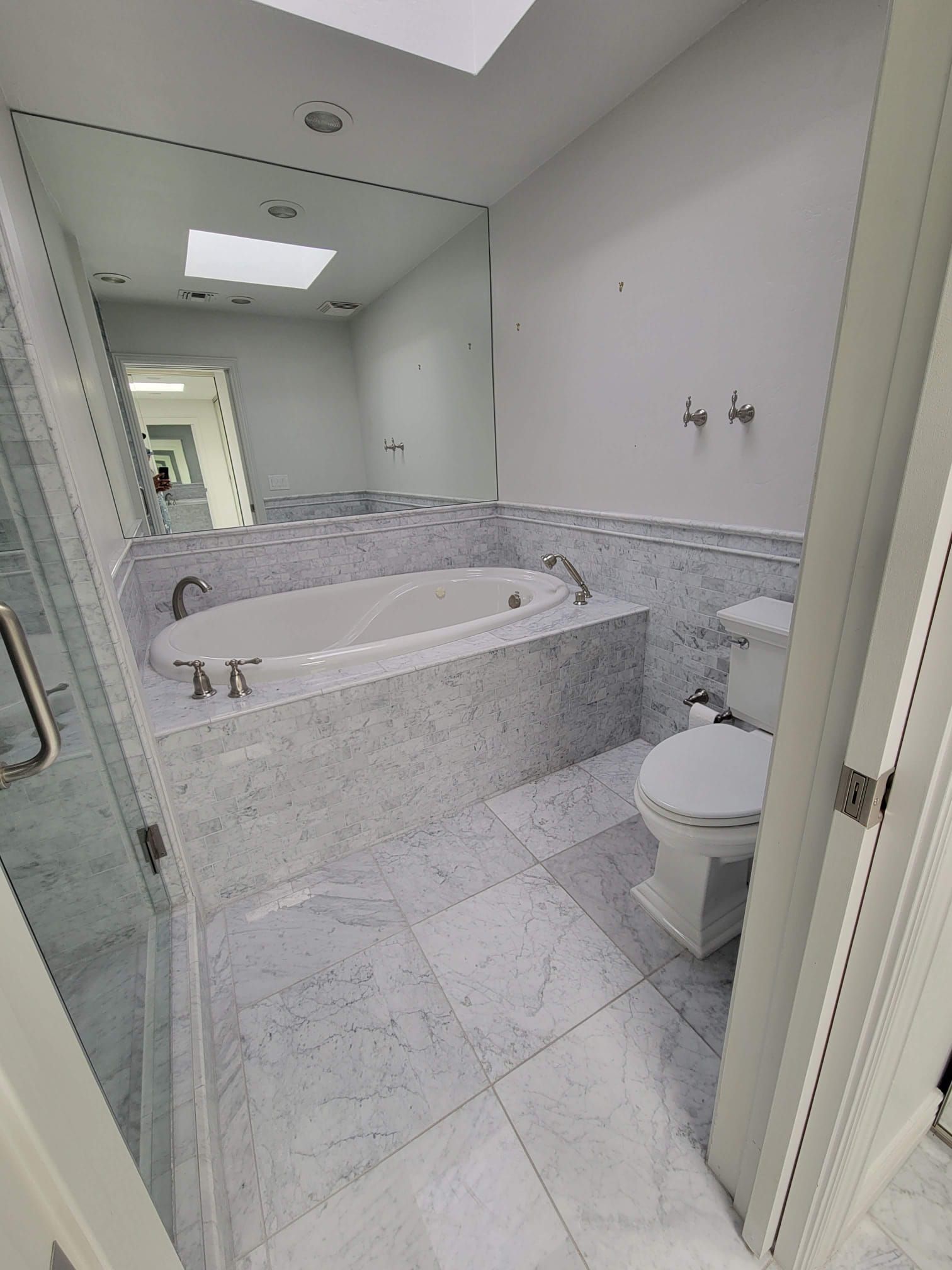 A bathroom with a tub , toilet , and mirror.