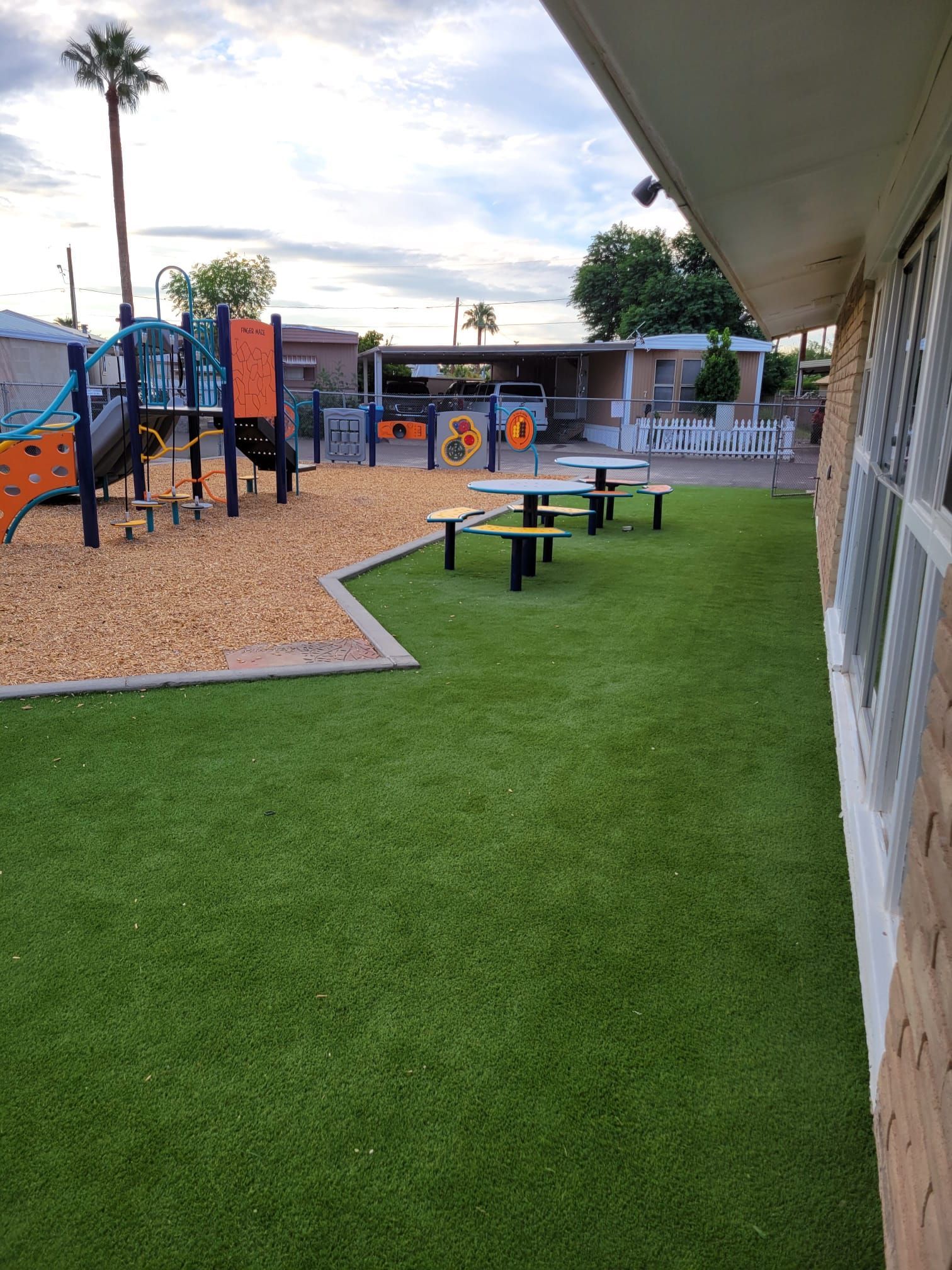 A playground with tables and benches in front of a building.
