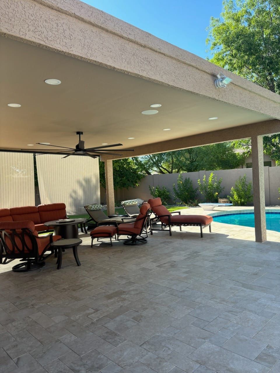 A patio with a ceiling fan and a swimming pool