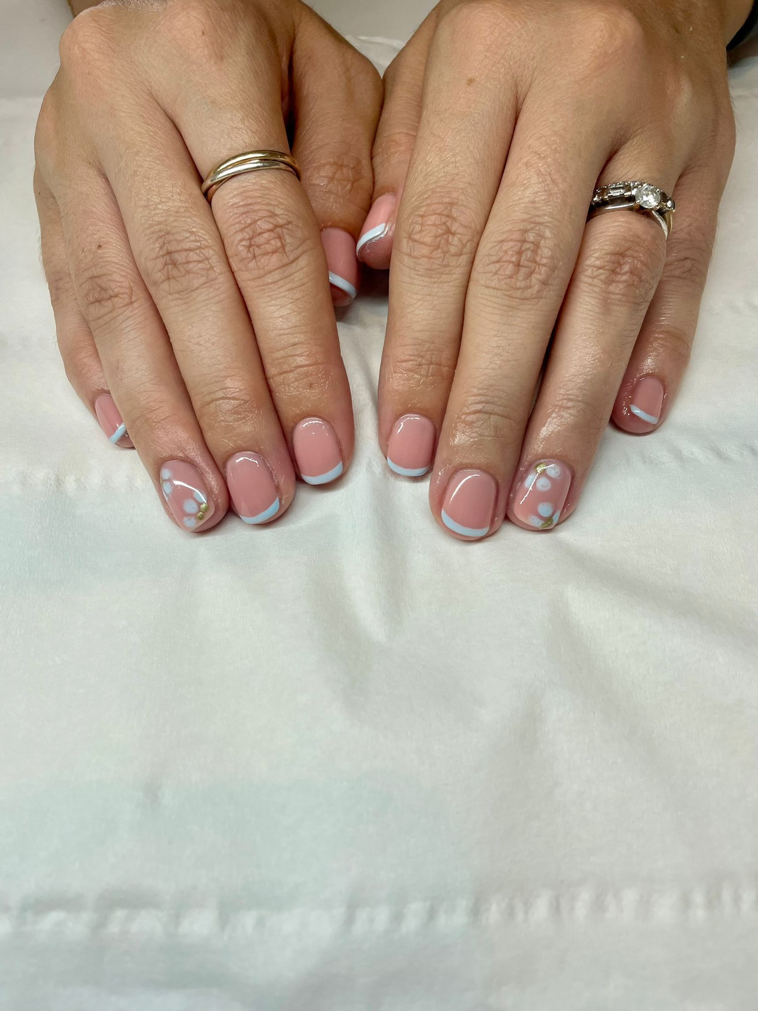 Hands with French tip nails, a pale pink base, and a silver border.
