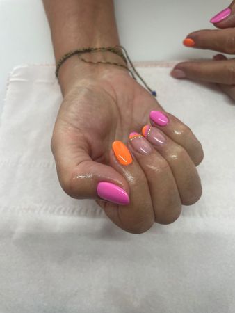 Hand with pink and orange polished nails, resting on a white surface.