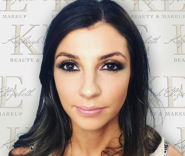 Woman with smoky eye makeup, looking at the camera. Neutral background with beauty studio logos.