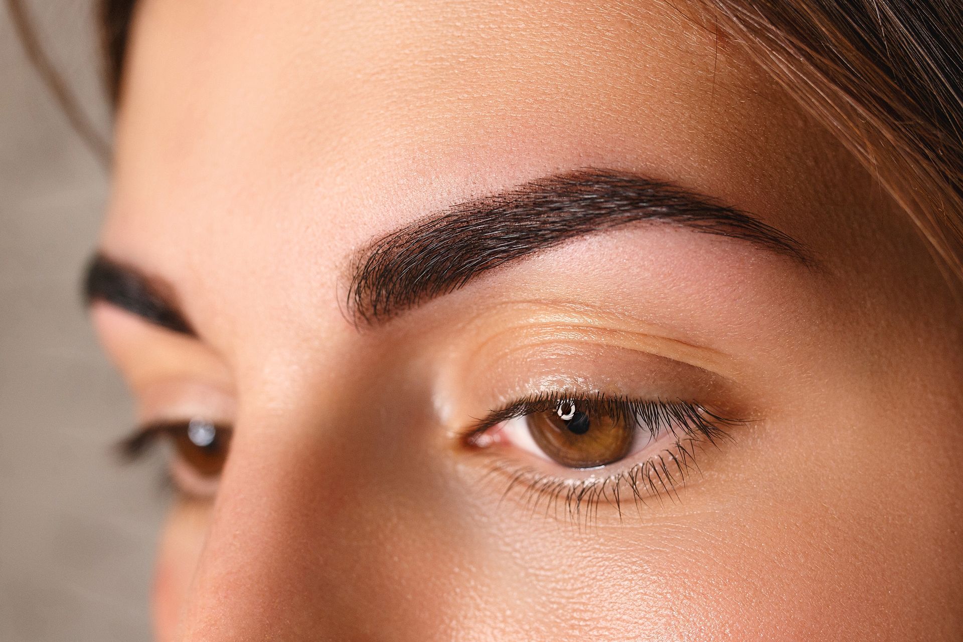 Close-up of a person's eye, showing a dark, well-defined eyebrow and a closed eyelid. Brown eye.