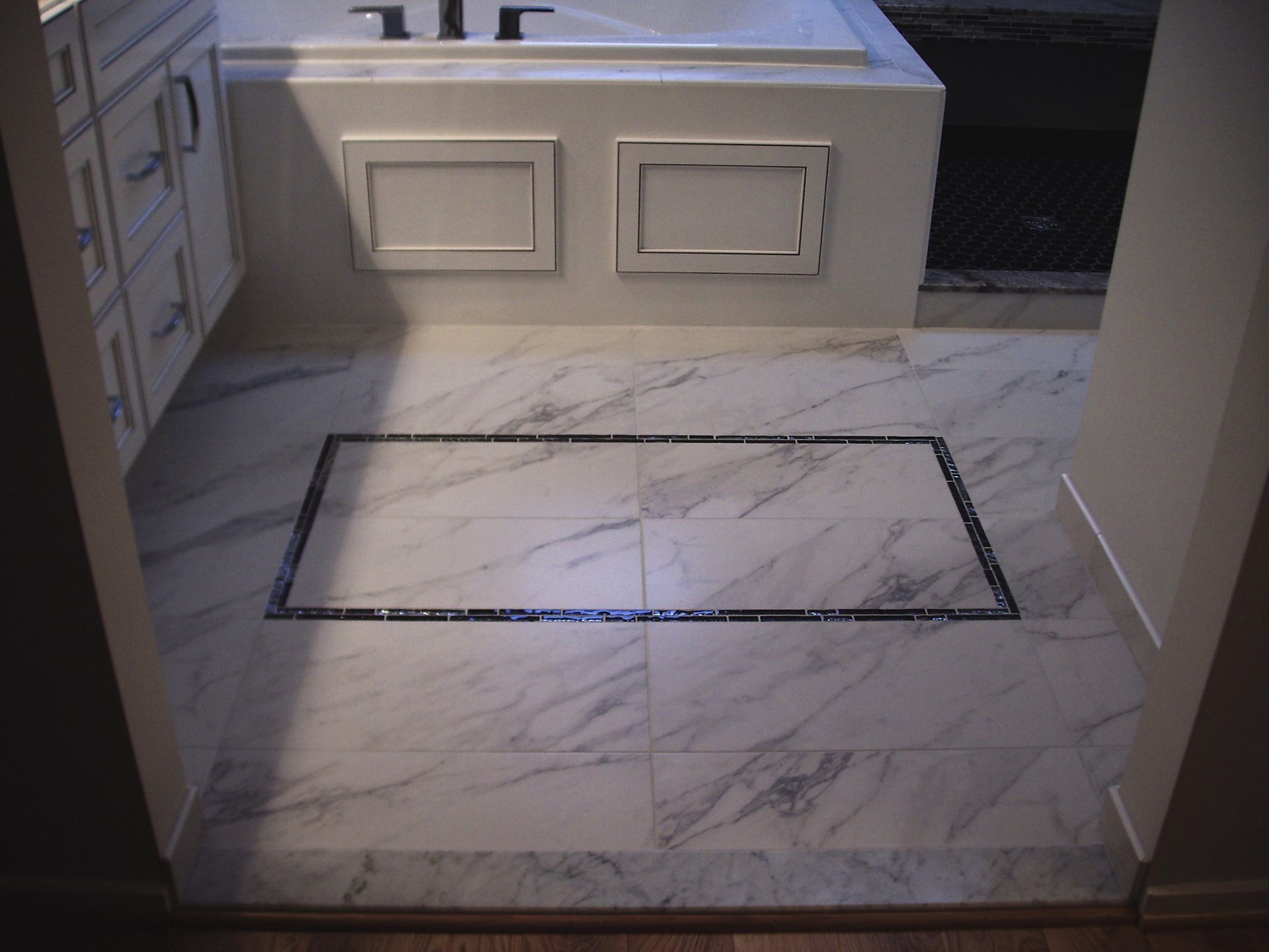 Bathroom with marble tile floor and a recessed rectangular drain with dark border.