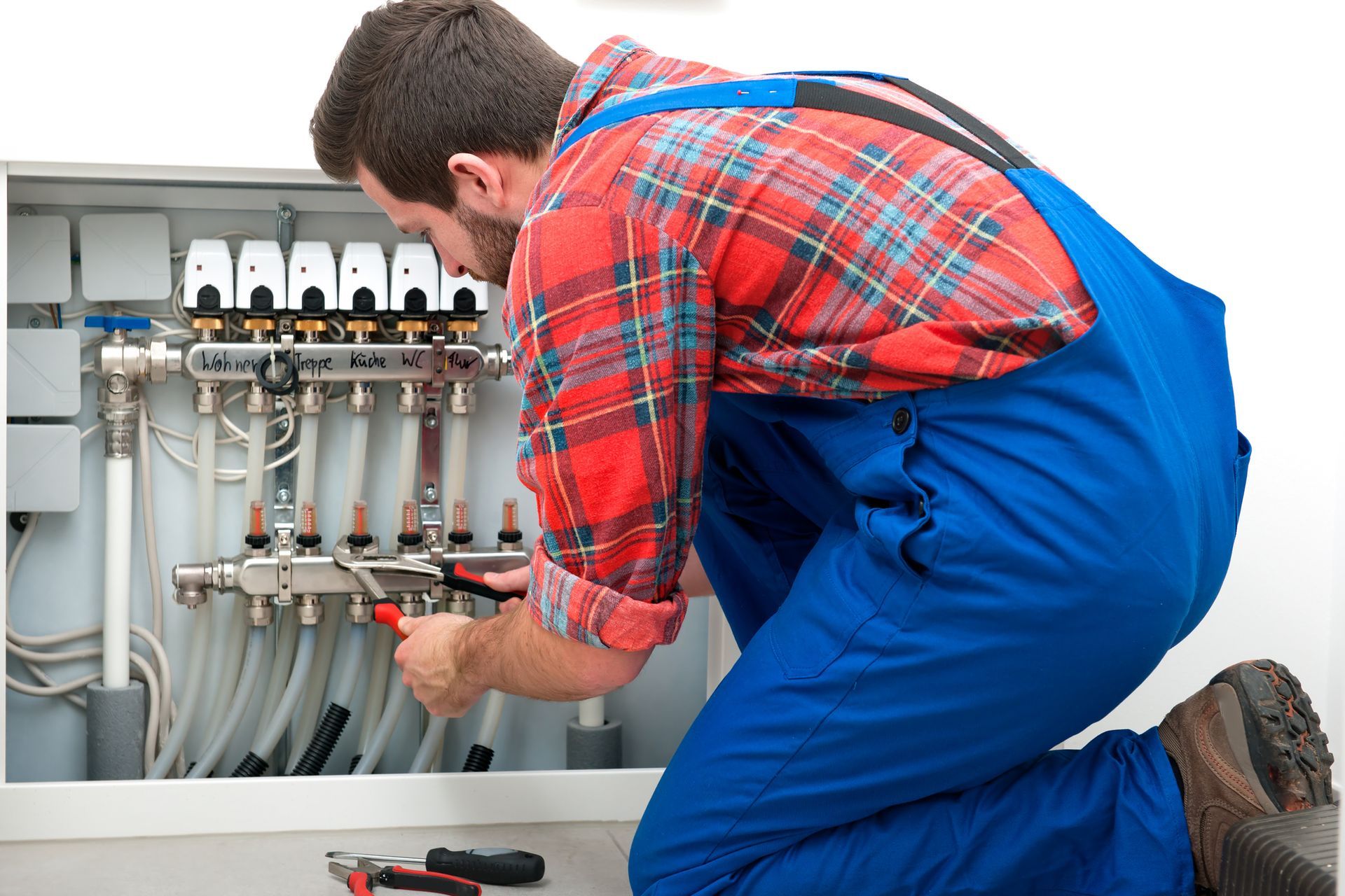 Person in blue overalls Working on a heating system | Heating in Catonsville, MD | John E. Ruth Co. Person in blue overalls Working on a heating system | Heating in Catonsville, MD | John E. Ruth Co.