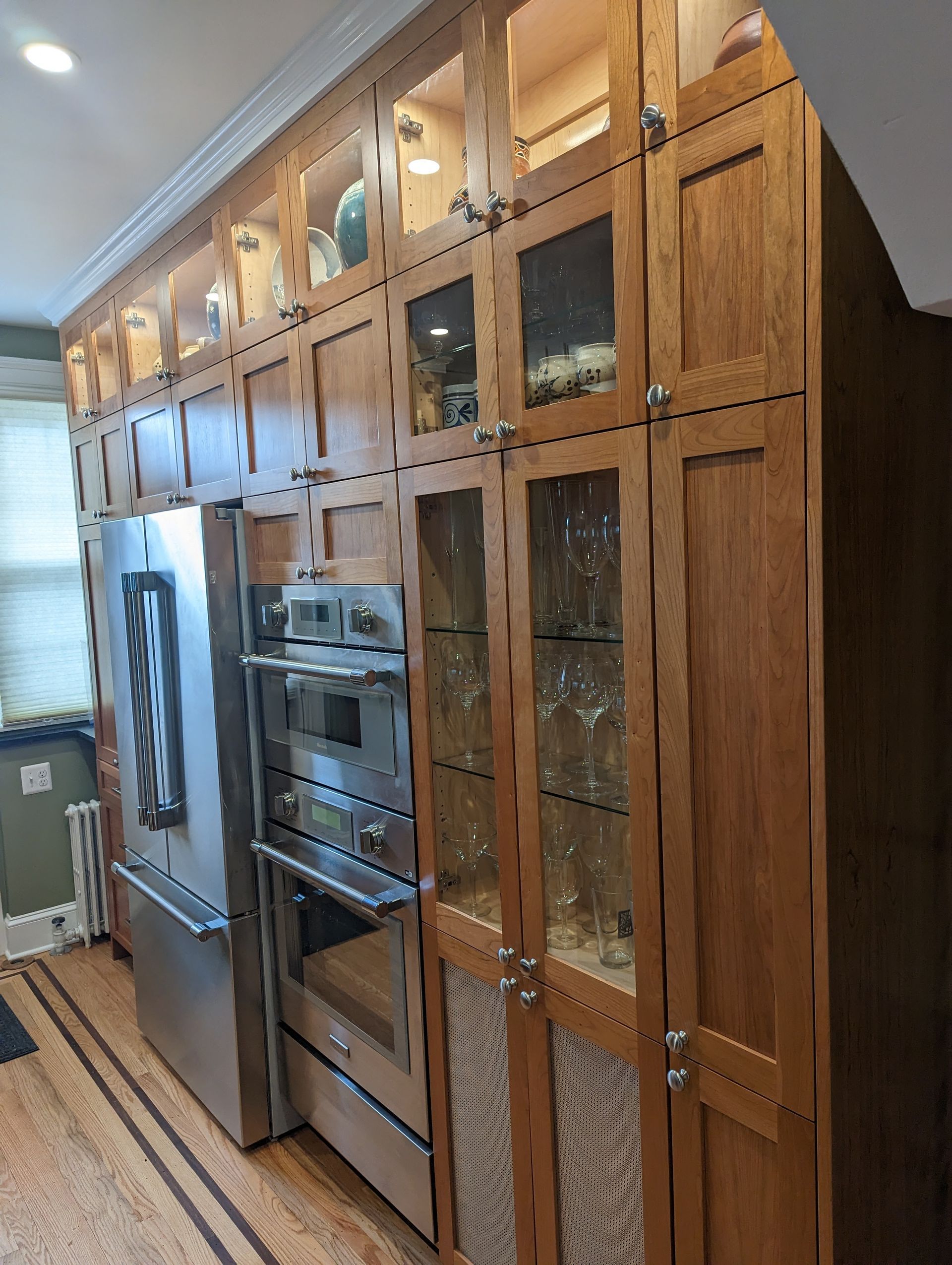 Wooden kitchen cabinets with glass doors, stainless steel appliances.