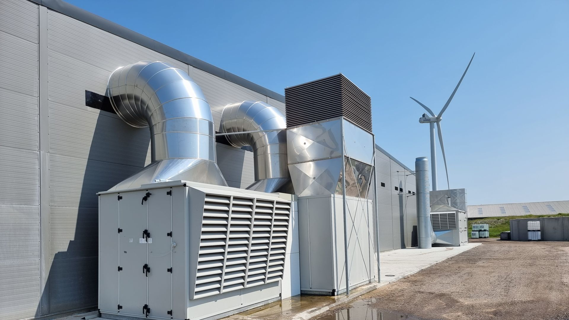Udvendigt af industribygning med udluftningsåbninger og en vindmølle.