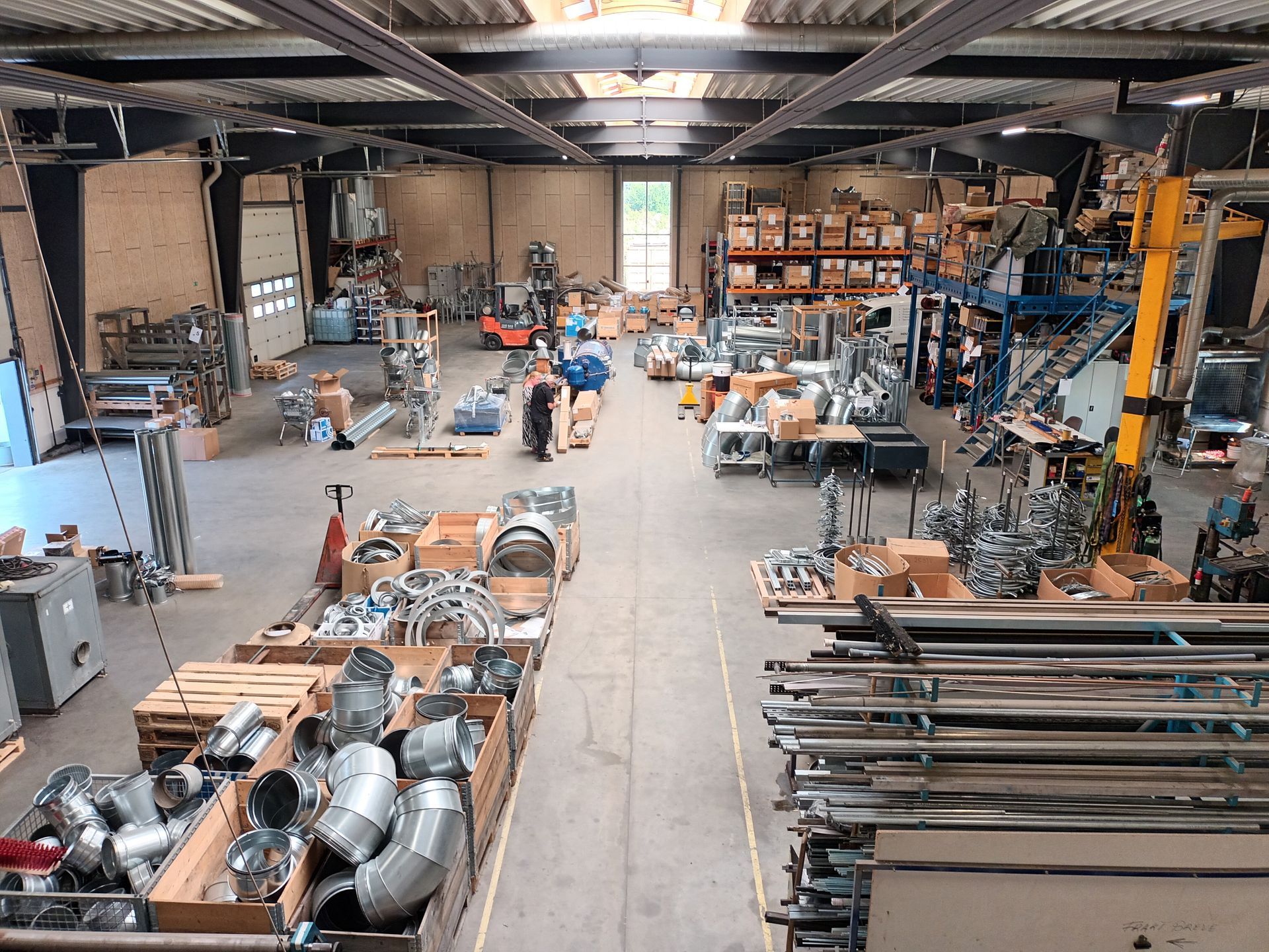 Stort lager med udstyr, reservedele og et par personer i arbejde.