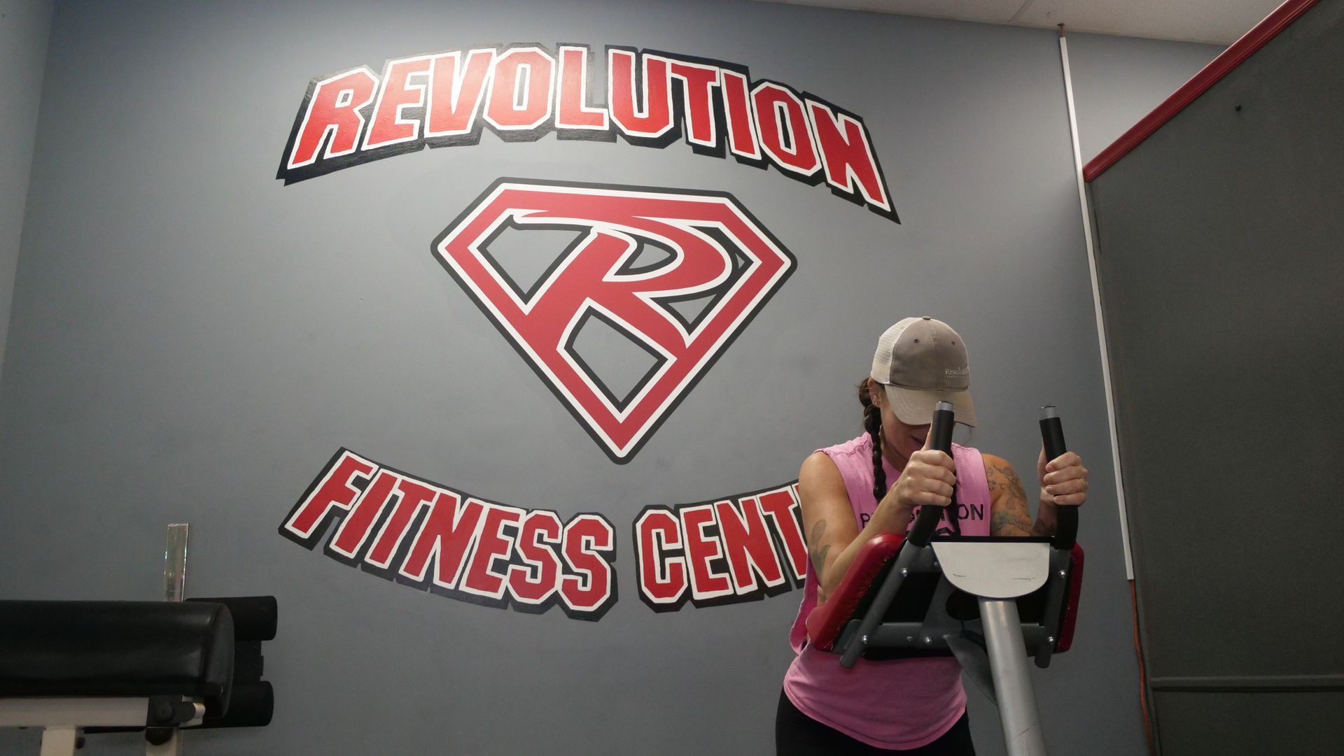 A woman is riding an exercise bike in a revolution fitness center