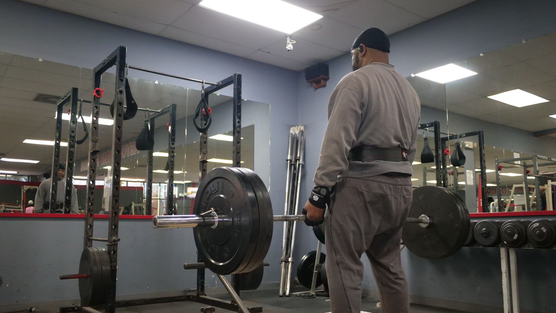 A man is holding a barbell in a gym.