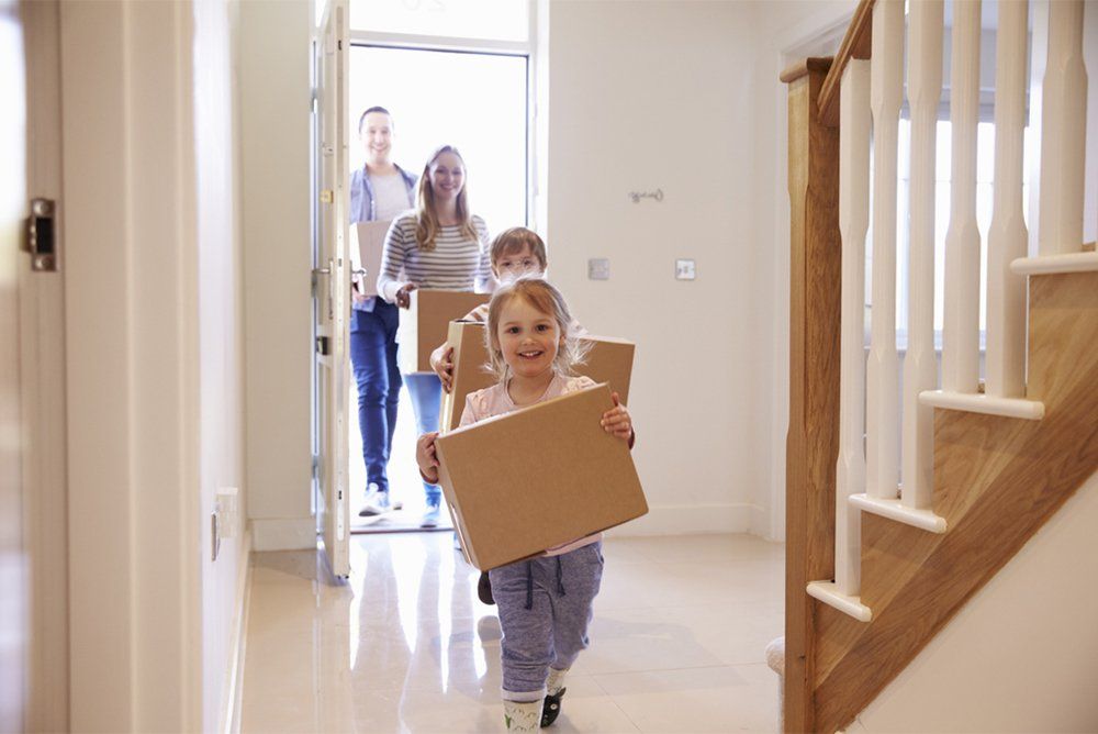 Family entering their new house with boxes