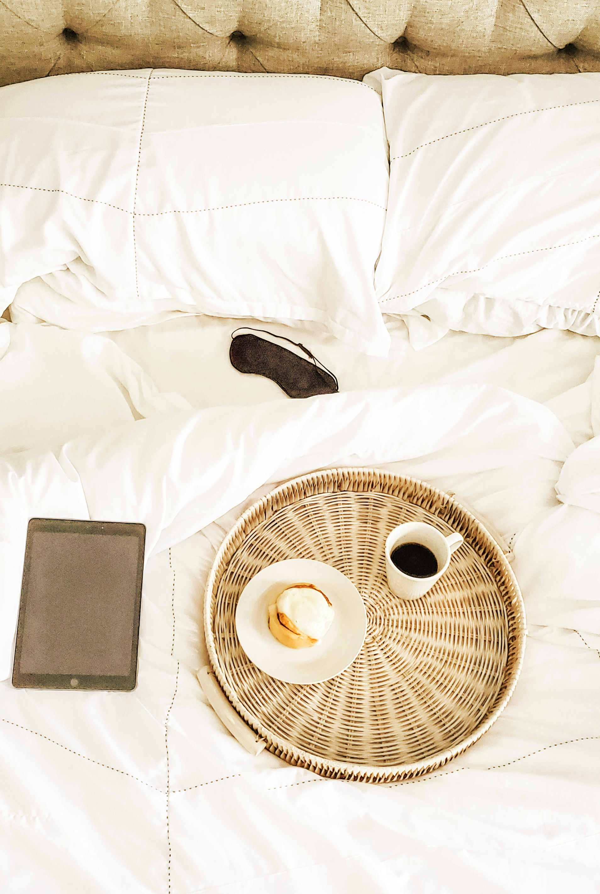 Person reading a book while reclining on a bed, wearing a light green shirt and gray jeans, with a blonde braid.