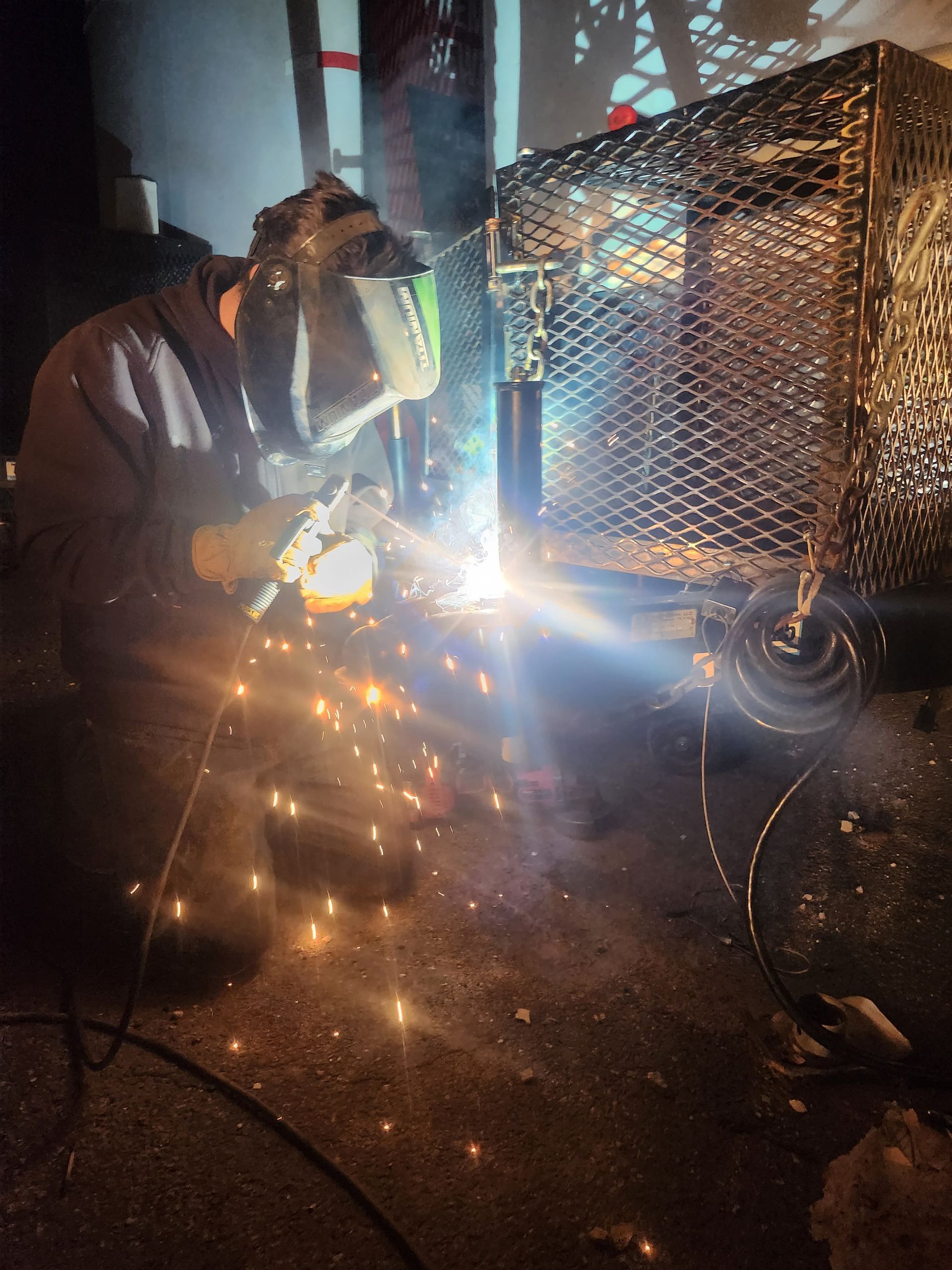 A man is cutting a piece of metal in front of a blue truck