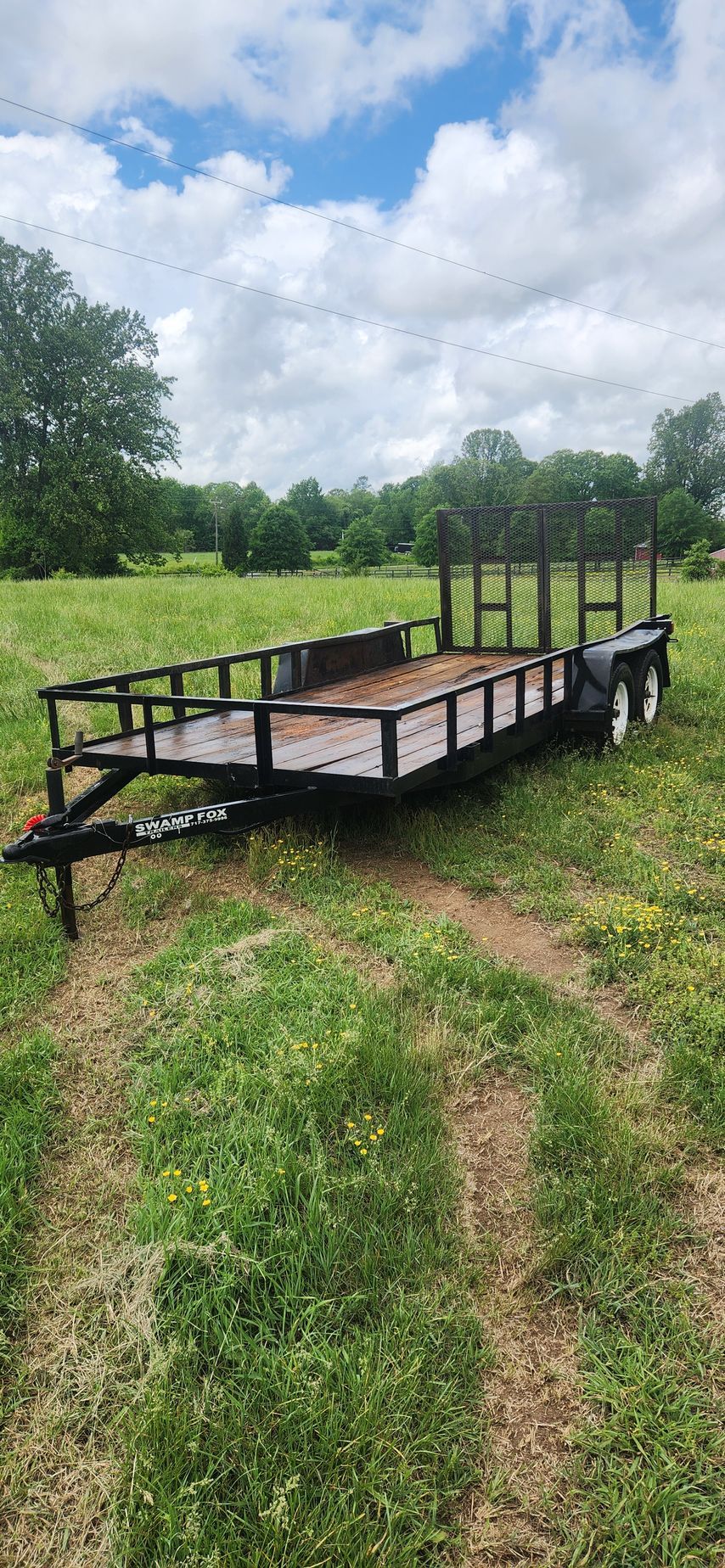 A trailer is sitting in the middle of a grassy field.