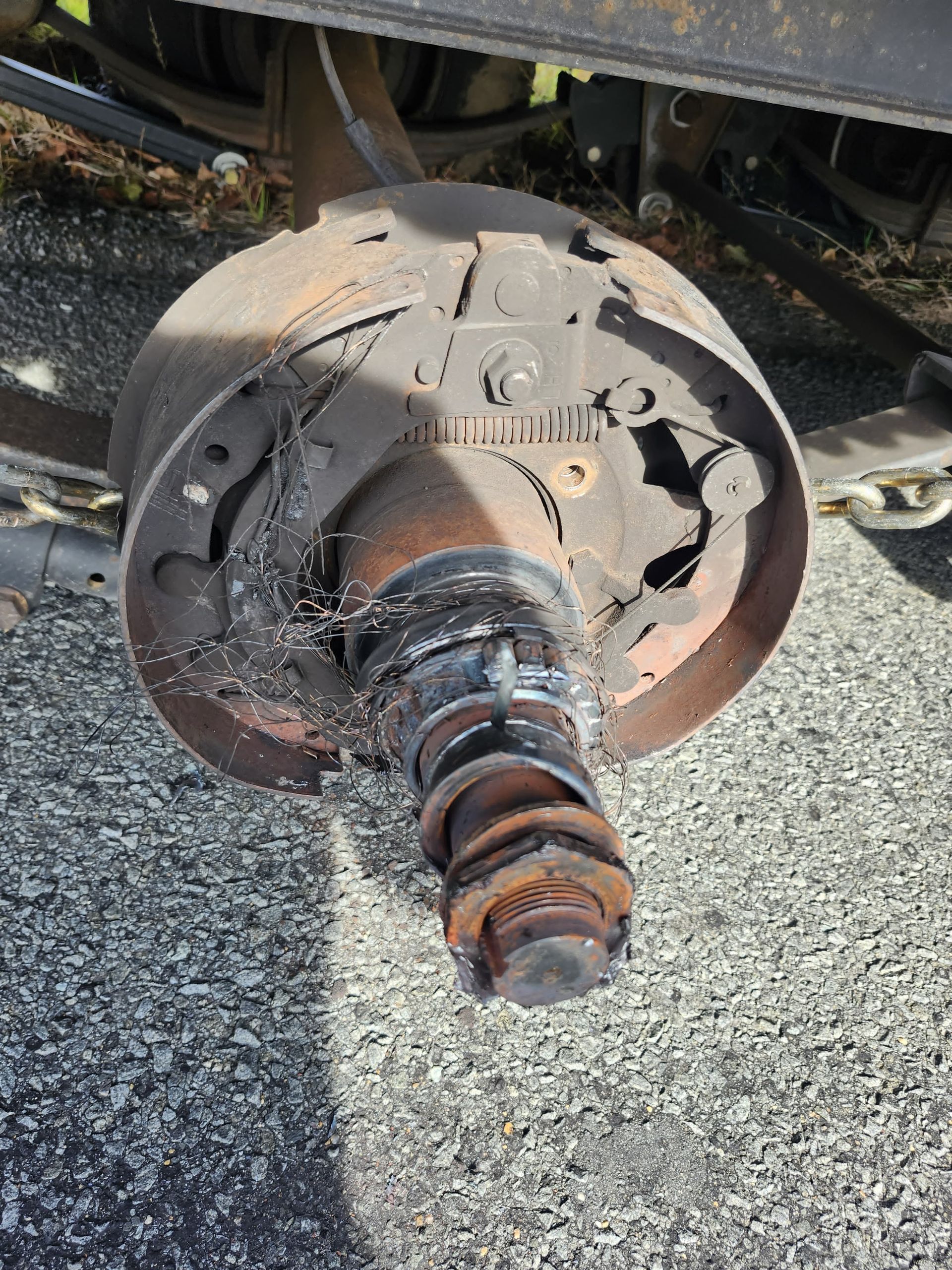 Damaged truck wheel hub assembly with detached brake components, appearing heavily worn, roadside.