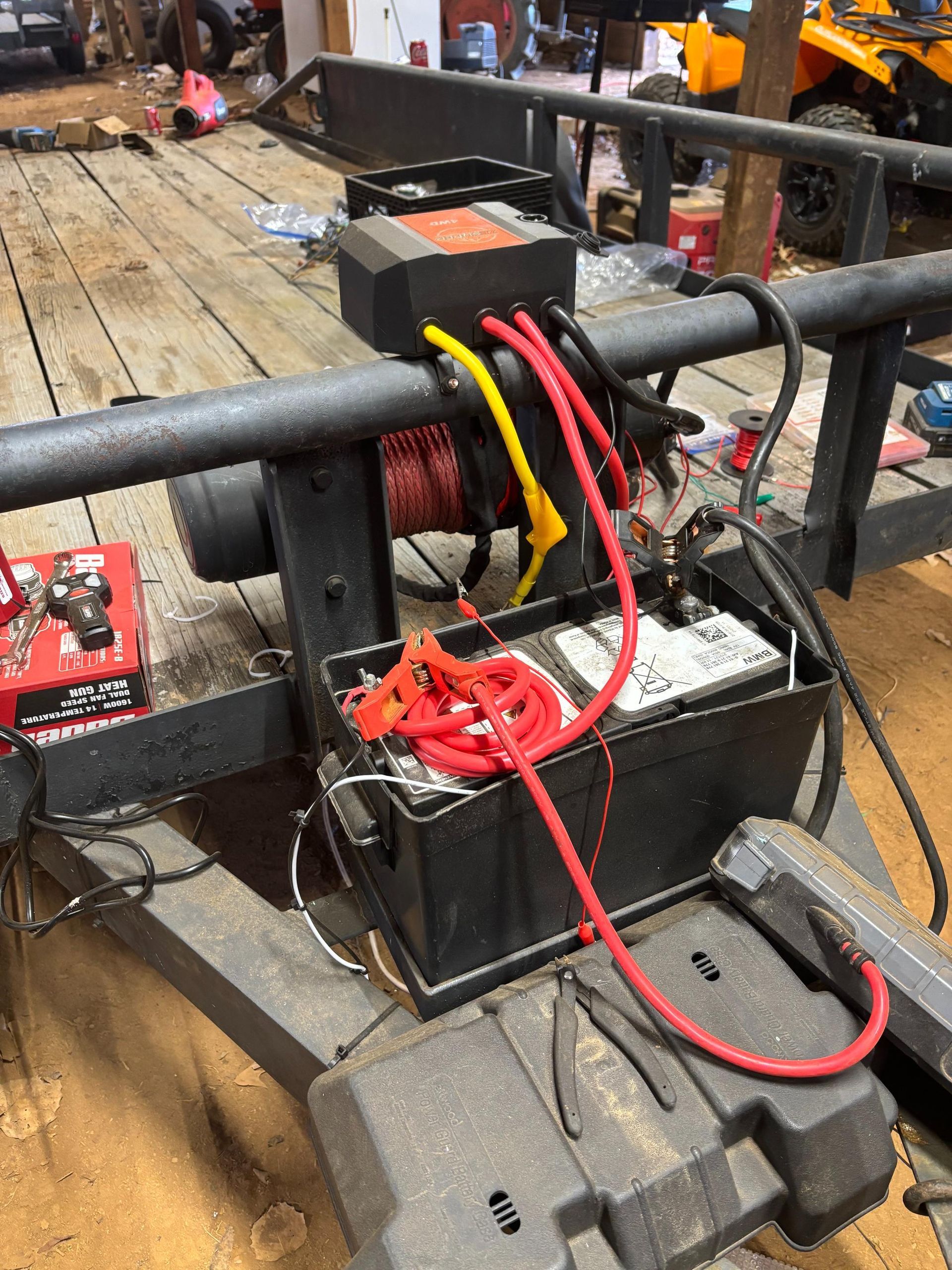 Trailer with a winch, batteries, and wiring. Black and red cables are visible, as well as a black box.