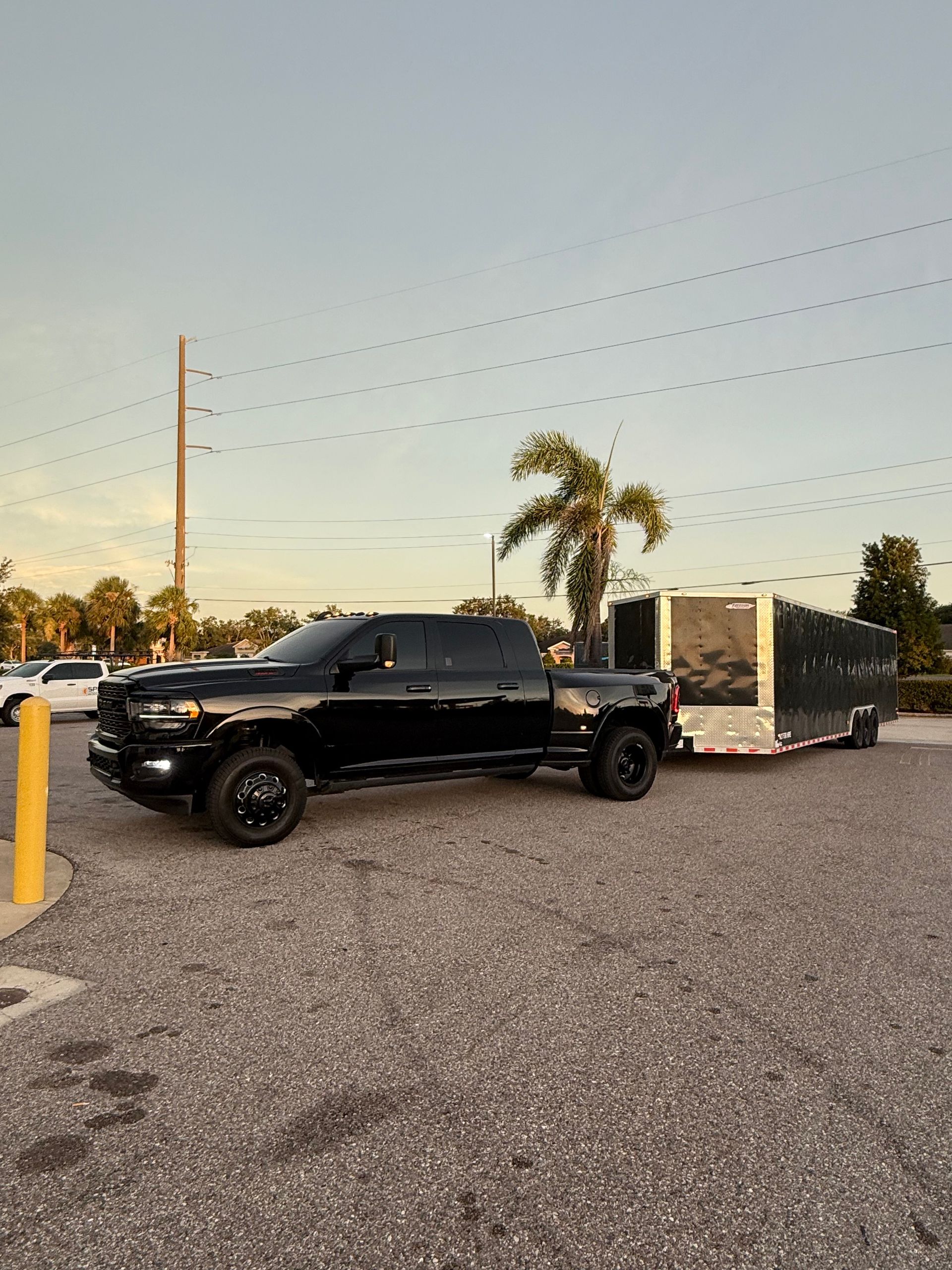 Black pickup truck pulling a silver trailer parked in a lot. Dusk setting.