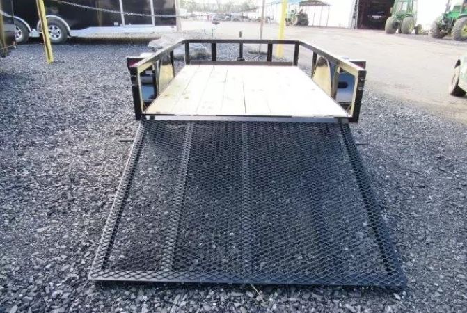 A small trailer is sitting on top of a gravel road.