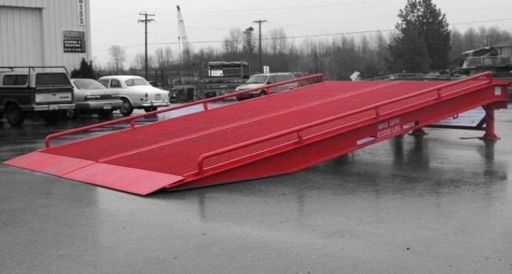 A red ramp is sitting in a parking lot next to a building.