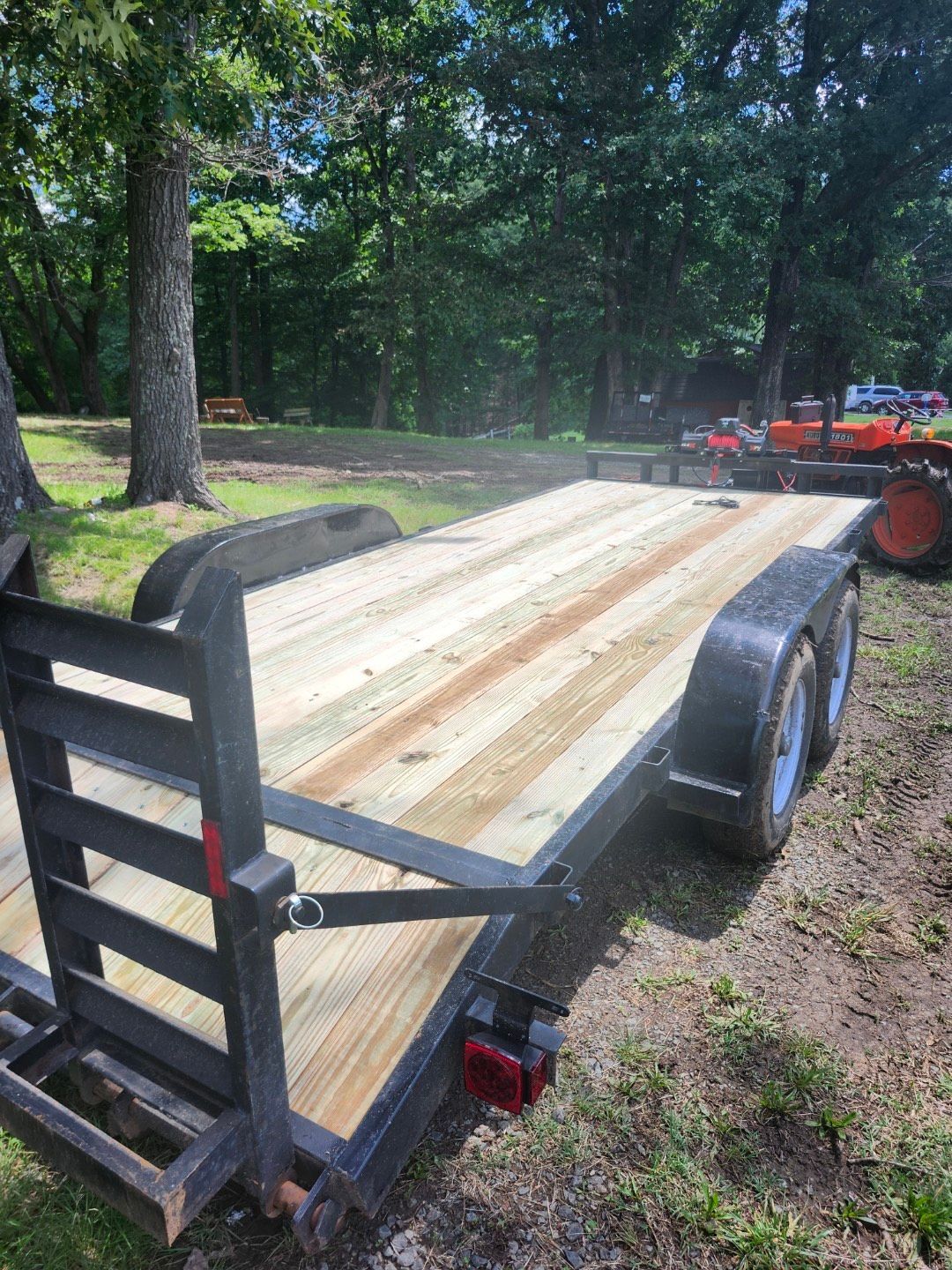 A trailer with a wooden deck is parked in the grass.