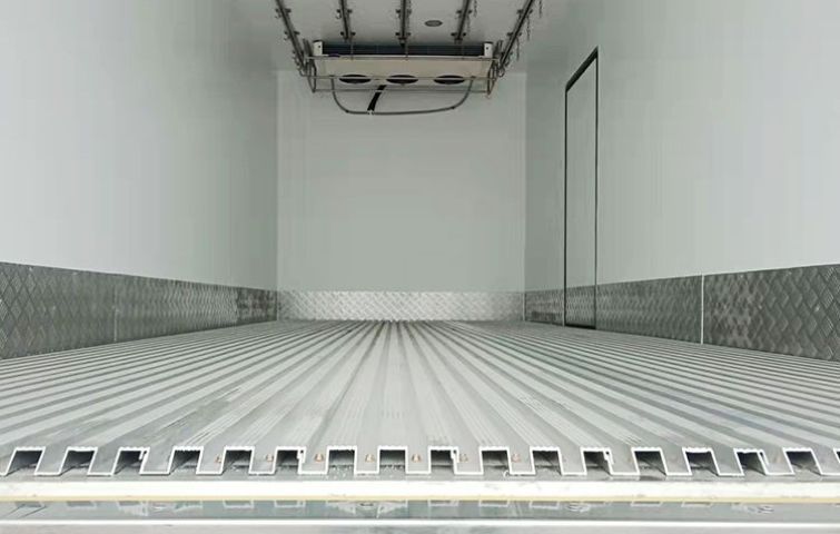The inside of a refrigerator truck with a refrigerator inside of it.