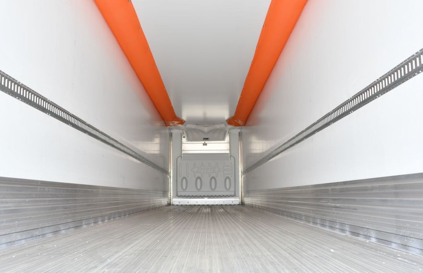 The inside of a semi truck with a white wall and orange stripes on the ceiling.