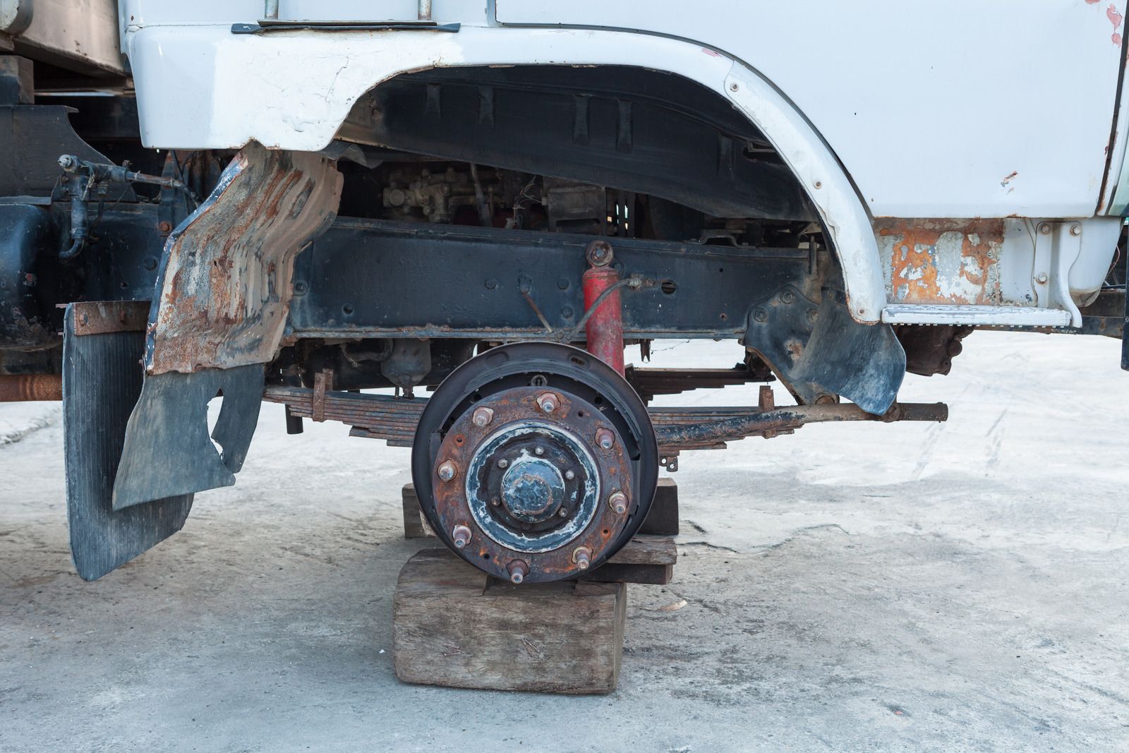 The rear wheel of a truck is sitting on a wooden block.