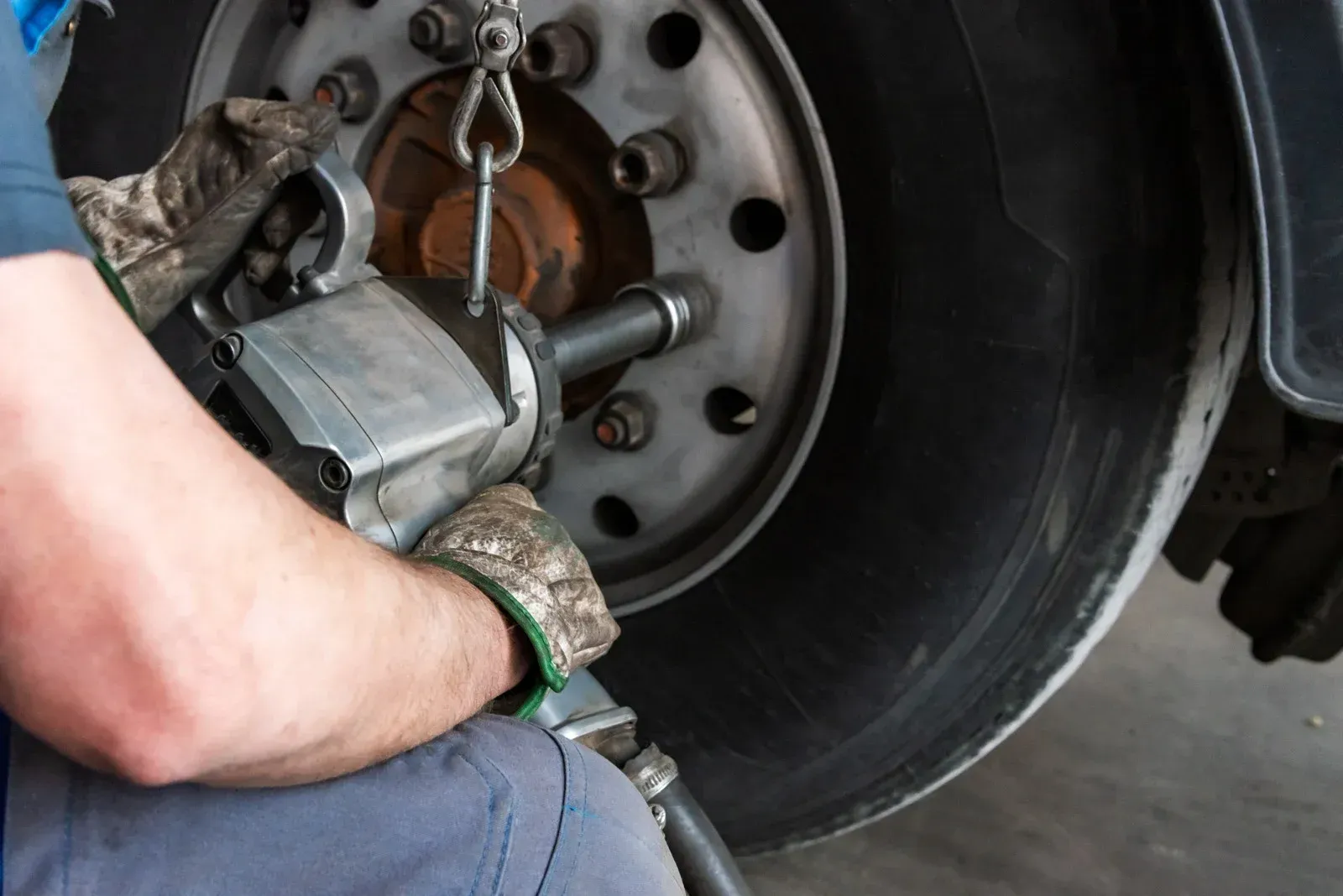 A man is working on a truck tire with a wrench.