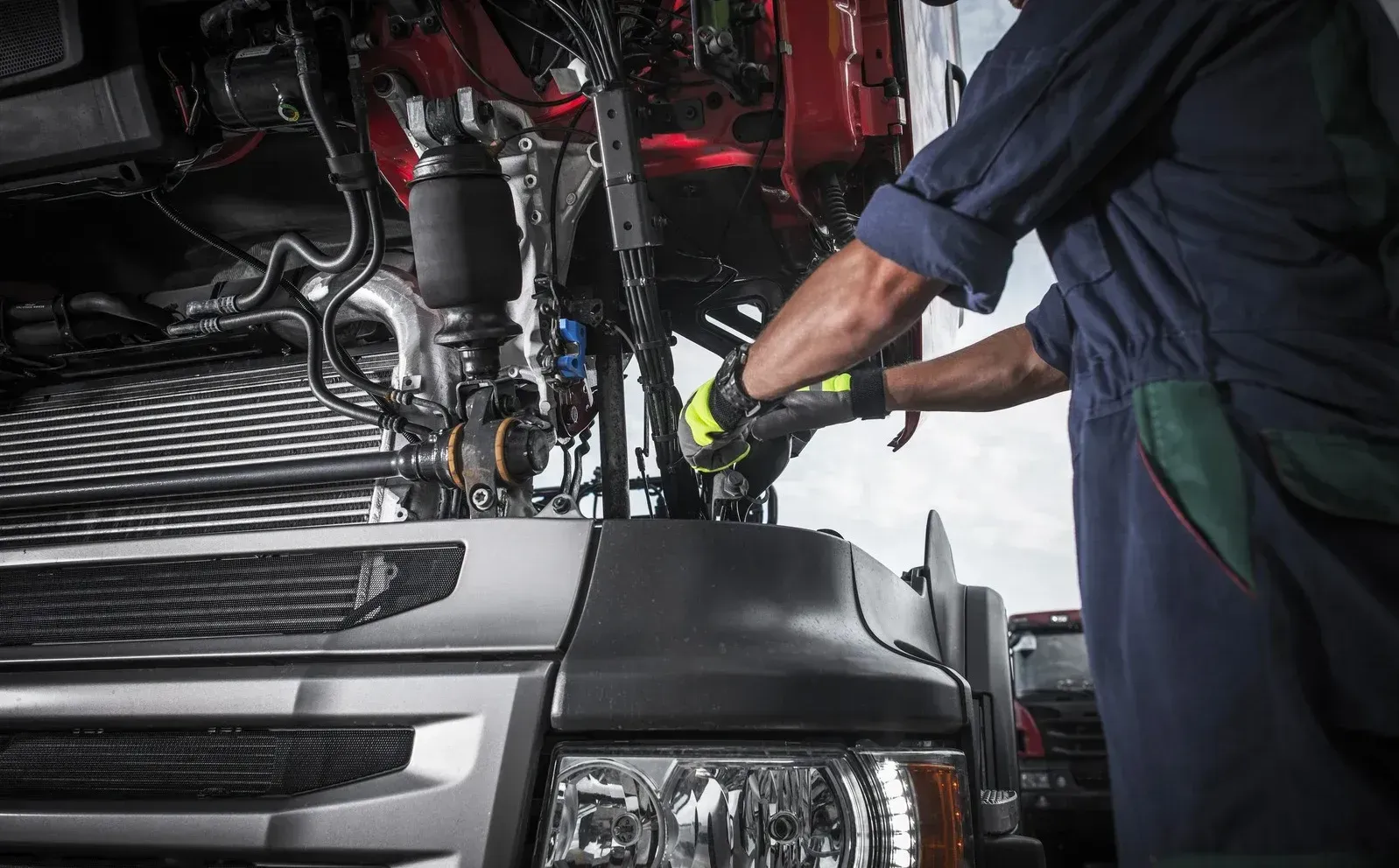 A man is working on the engine of a truck.