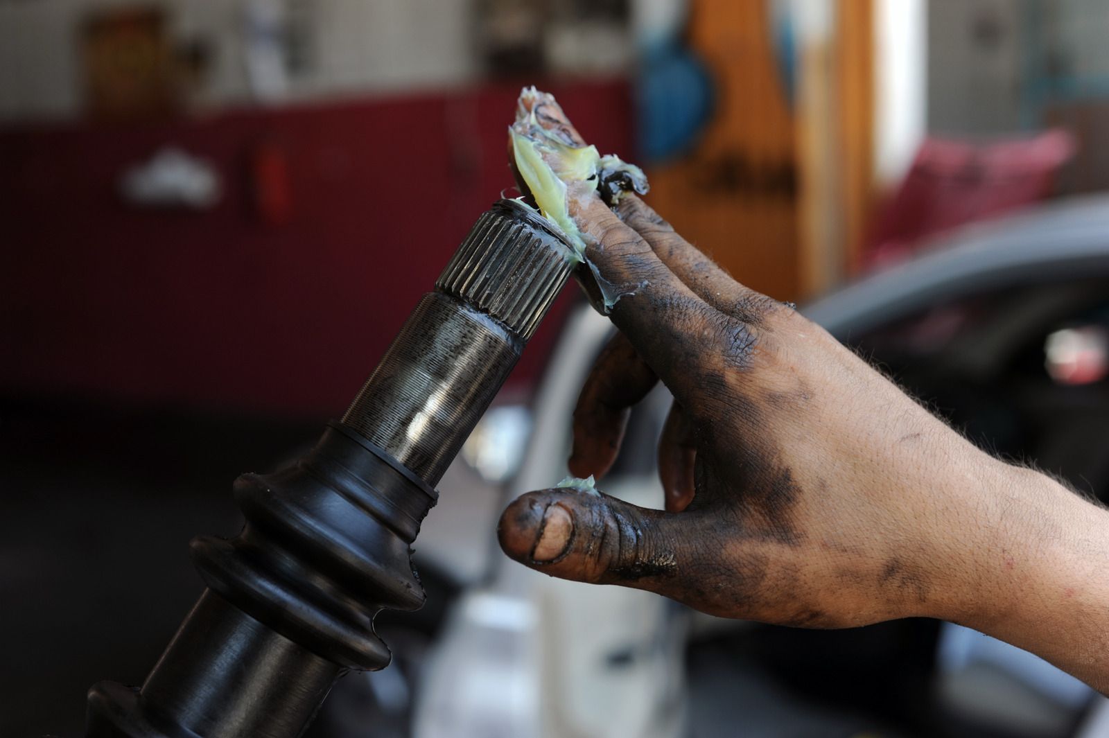 A dirty hand is holding a piece of metal