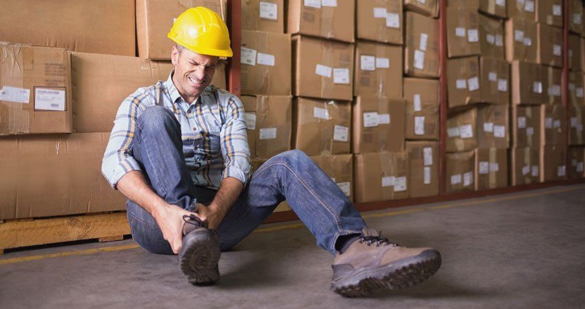 man in hard hat holding injured leg