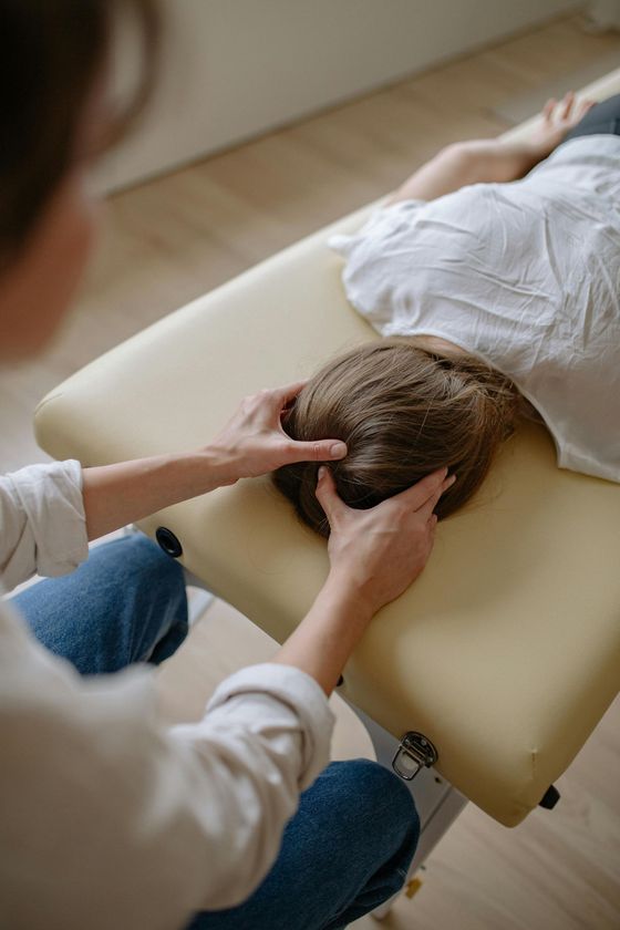 A woman is giving a child a head massage on a table.