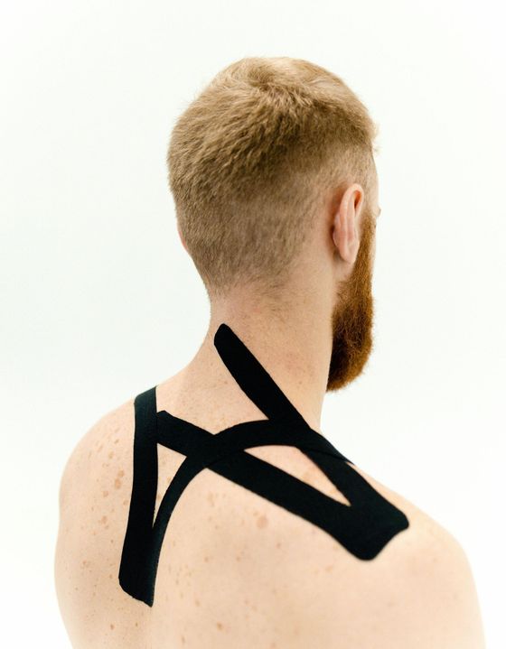 A man with a beard has black tape on his back