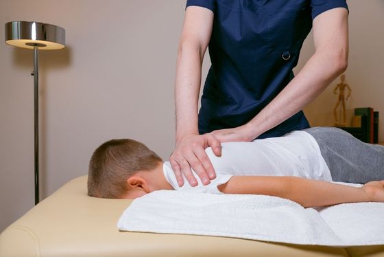 A young boy is laying on a table getting a massage.