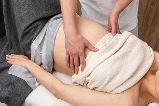 A woman wrapped in a towel is getting a massage from a man.