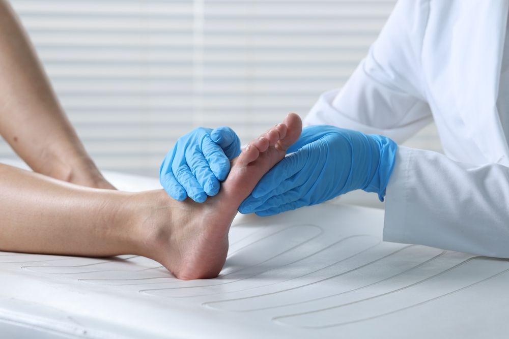 A doctor is examining a patient 's foot with blue gloves.