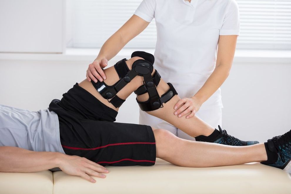 A woman is helping a man with a knee brace.