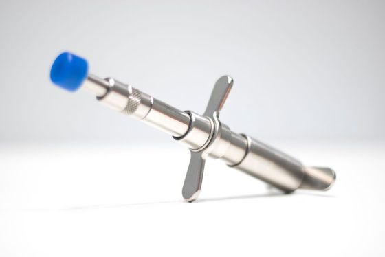 A close up of a metal object with a blue cap on a white surface.