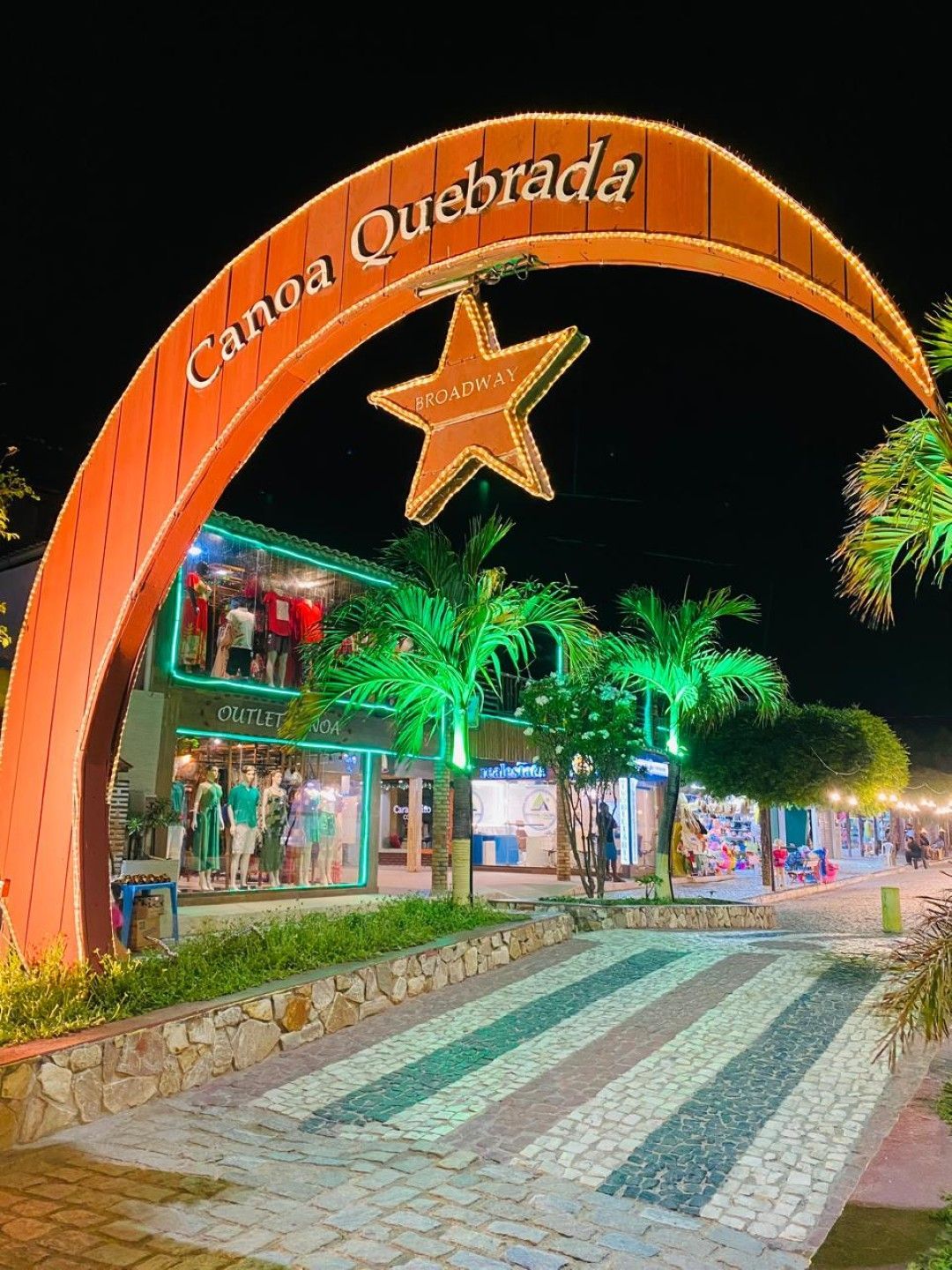 Casa de praia moderna em tons de bege e marrom, com uma pequena piscina, palmeiras e vista para o mar.