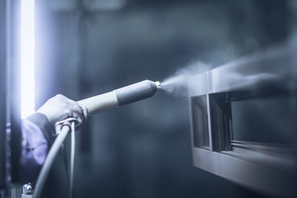 A Person Is Spraying Powder Paint on A Piece of Metal — Betts Welding Pty Ltd In Moss Vale, NSW