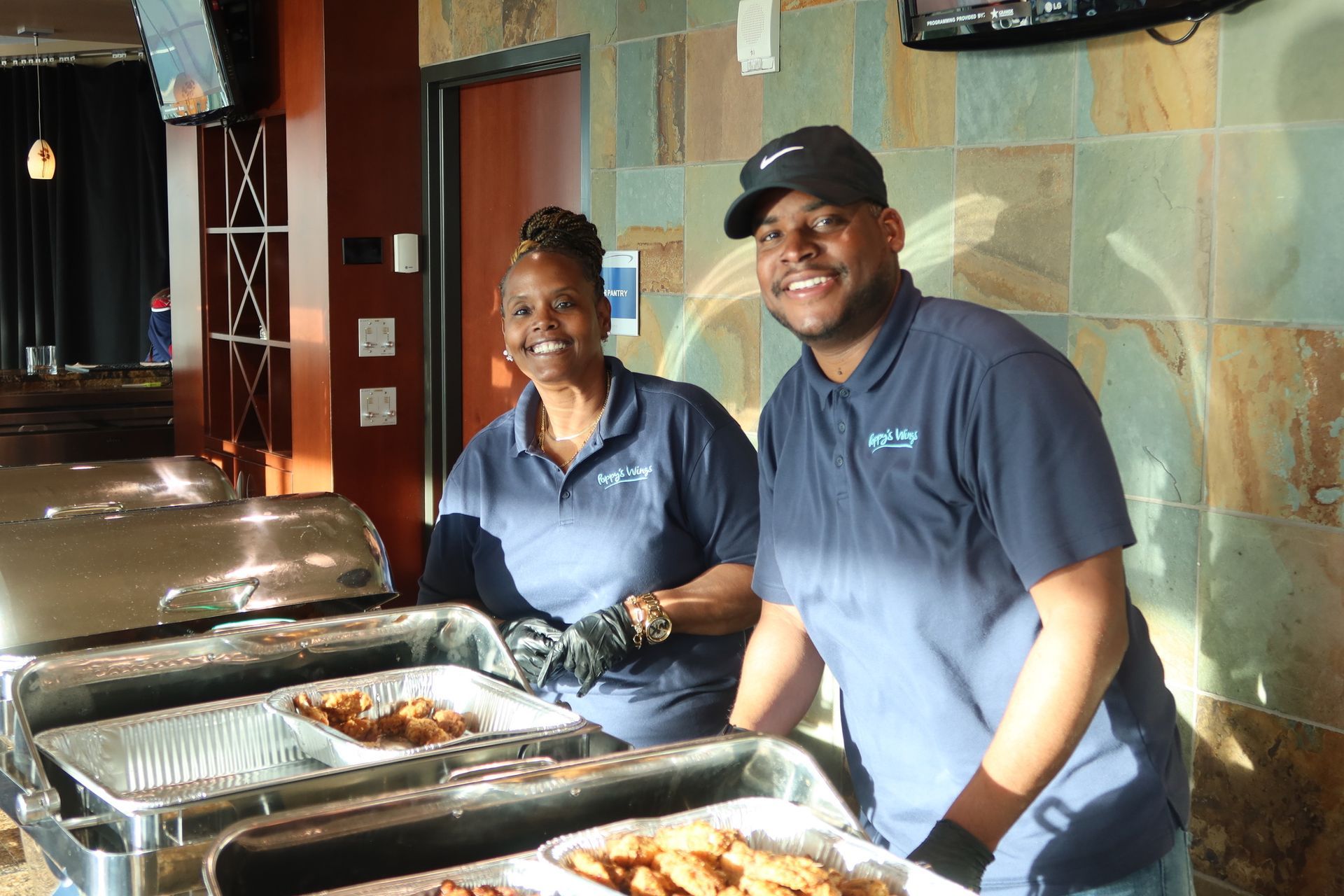 A man and a woman are standing in front of a buffet line.