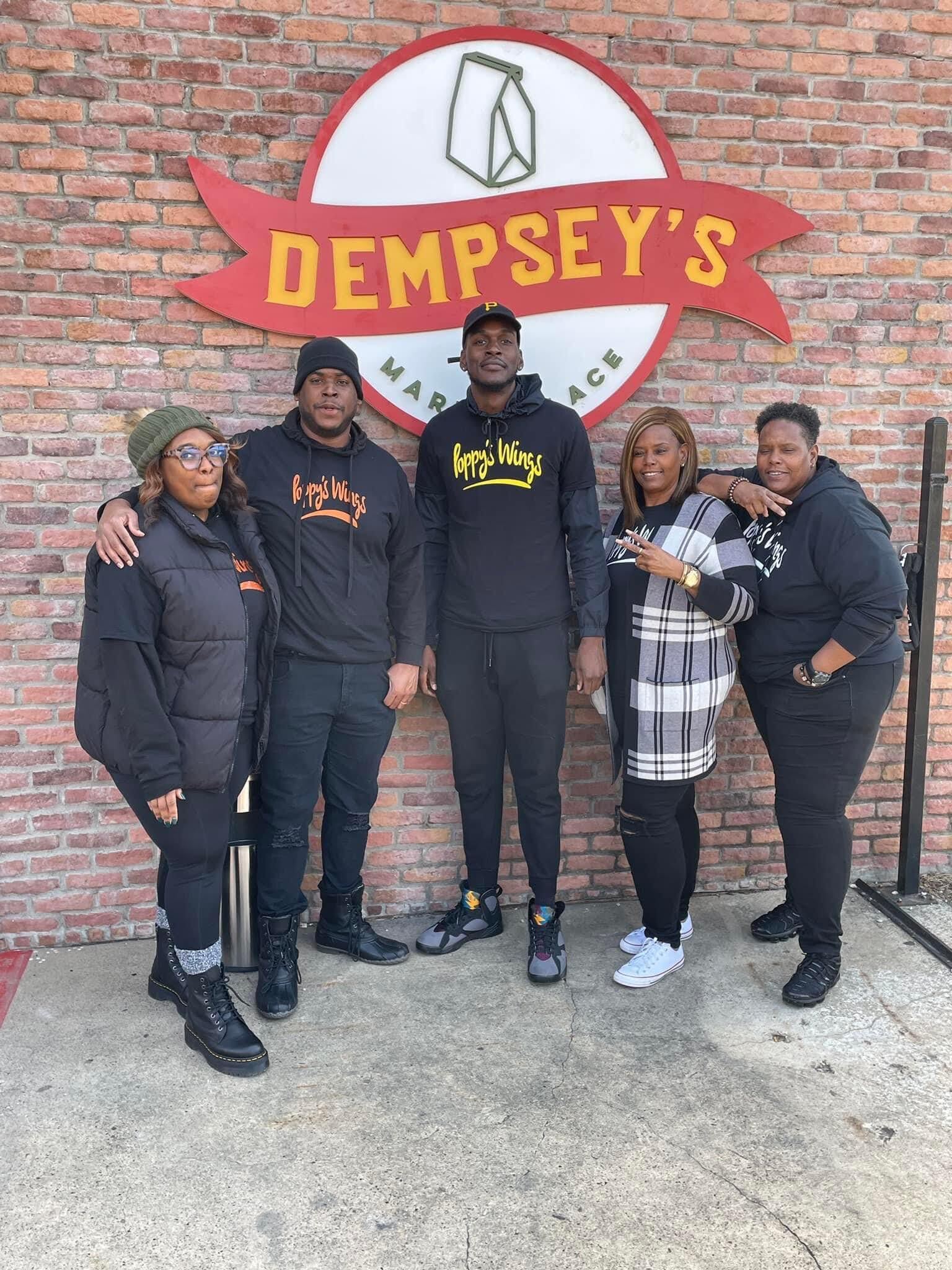 A group of people are posing for a picture in front of a brick wall.