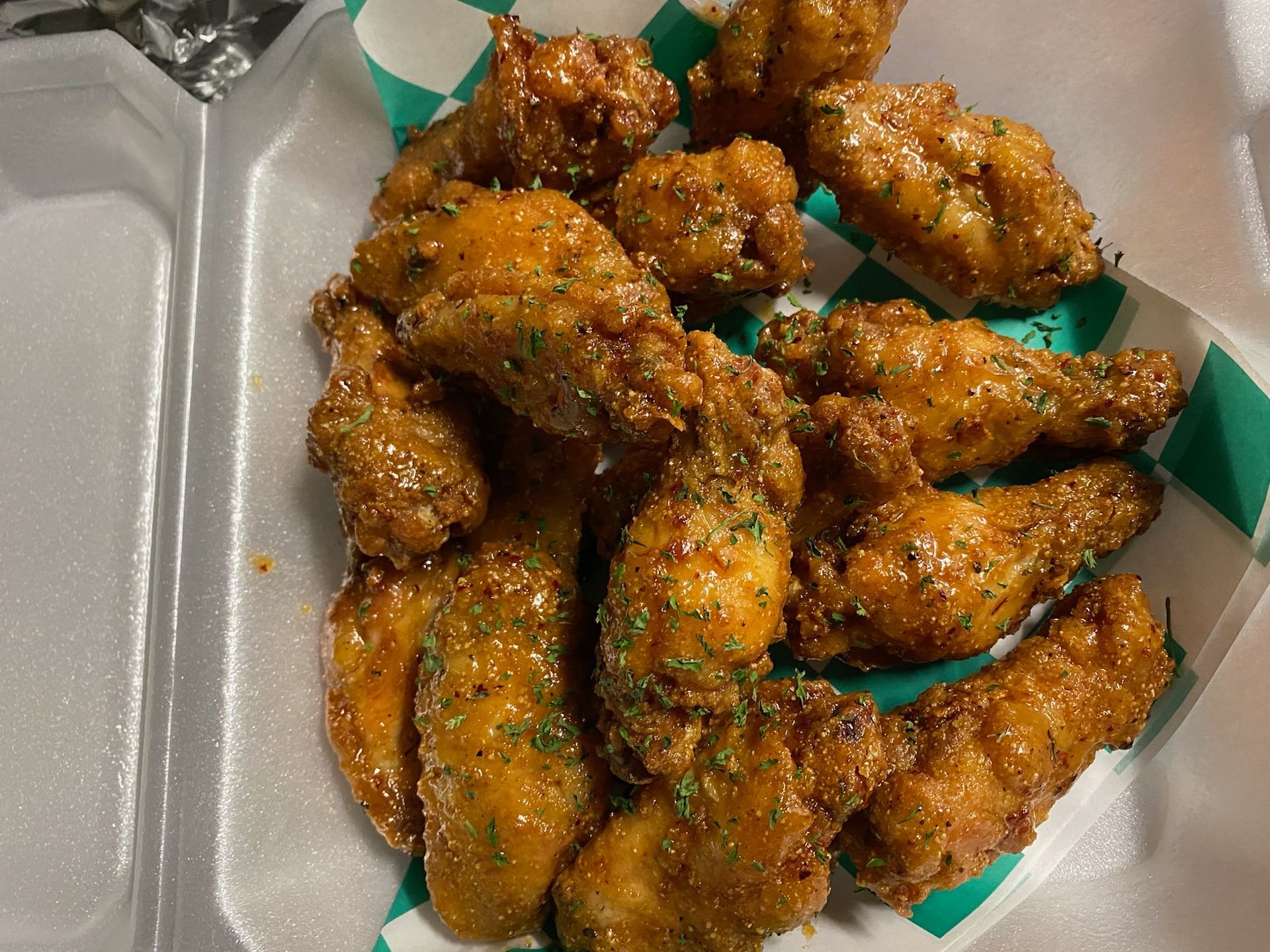 A tray of fried chicken wings in a styrofoam container.