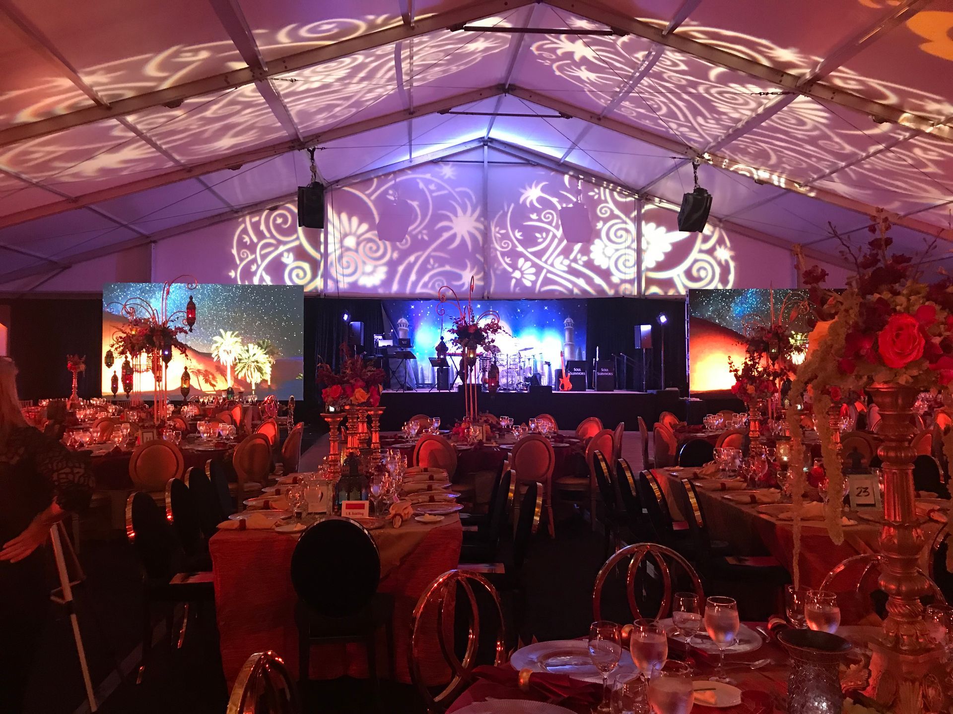 A large tent filled with tables and chairs and a stage.